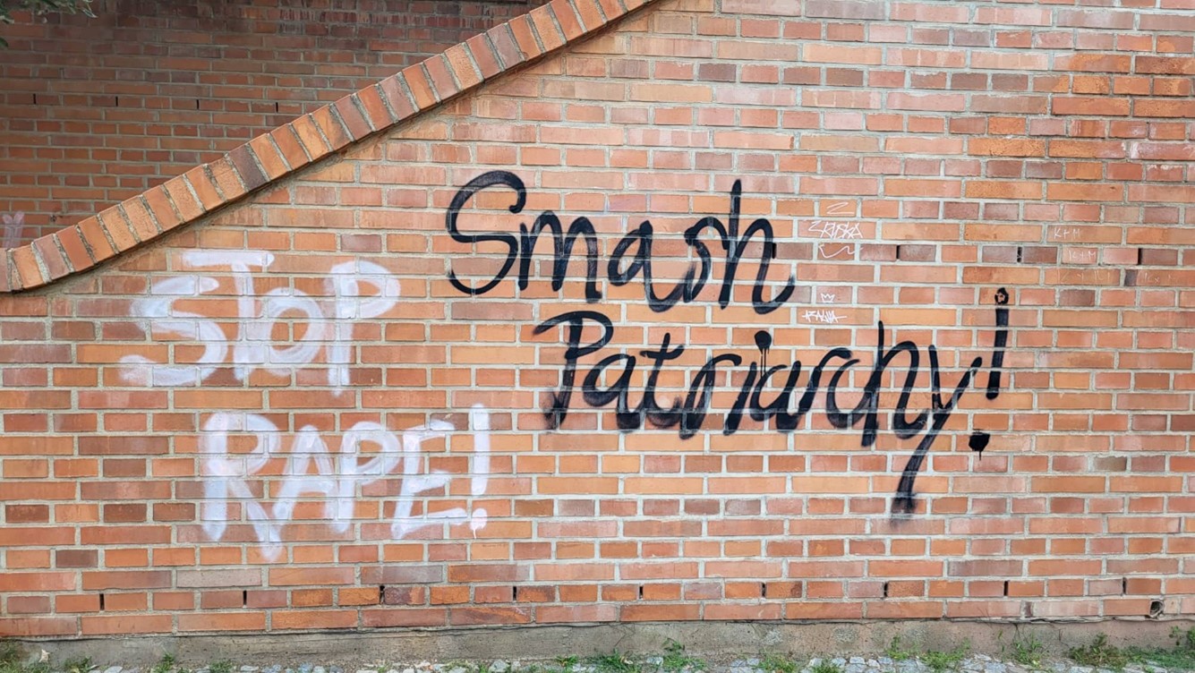 Graffity on a brick wall depicting the words Smash the Patriarchy (in black) and Stop Rape (in white)